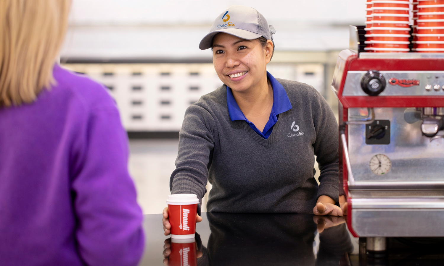 Serving coffee over counter to a customer