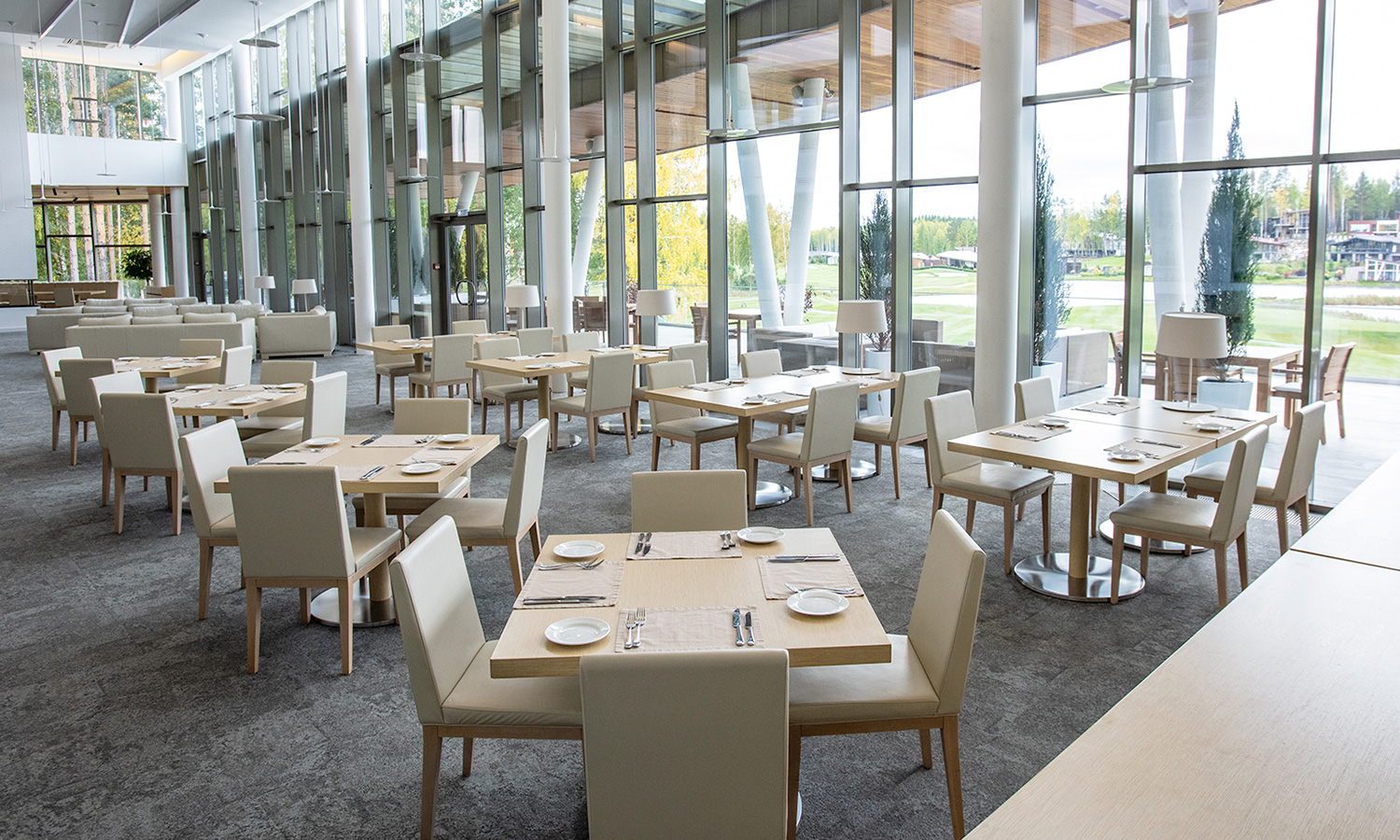 a bright and open commercial meeting space with high ceilings with seating for casual dining in the foreground and lounging at the back of the room